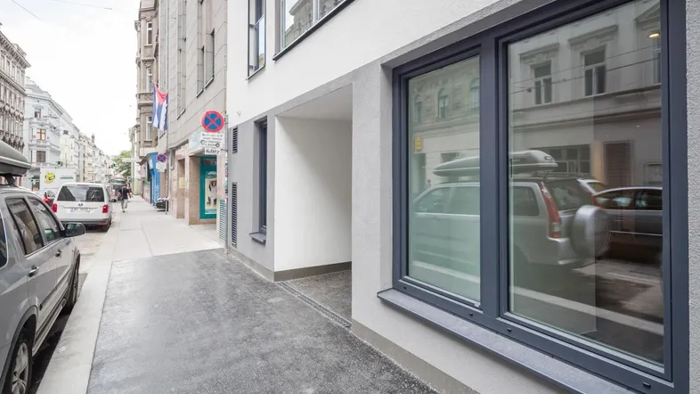 Moderne Geschäftsfassade mit großen Fenstern und Eingangsbereich an einer belebten Stadtstraße.