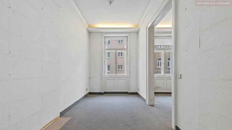 Leerer Raum in Renovierung mit Blick auf ein gegenüberliegendes Gebäude und einfachem Fenster.