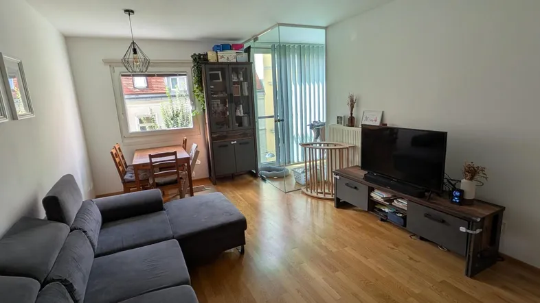 Gemütlicher Wohn-Essbereich mit Sofa, Fernseher und Esstisch, ideal für entspannte Stunden und gemeinsame Mahlzeiten.