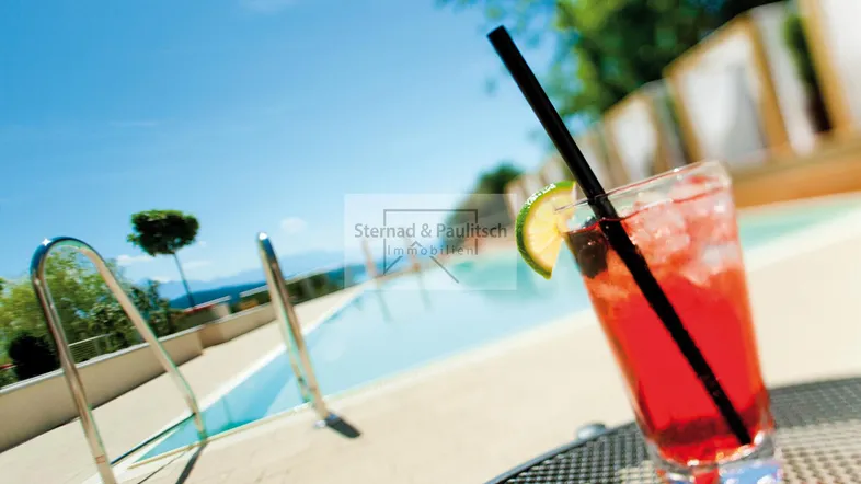 Erfrischender Cocktail am Pool mit malerischem Blick auf den See und die umliegenden Berge.