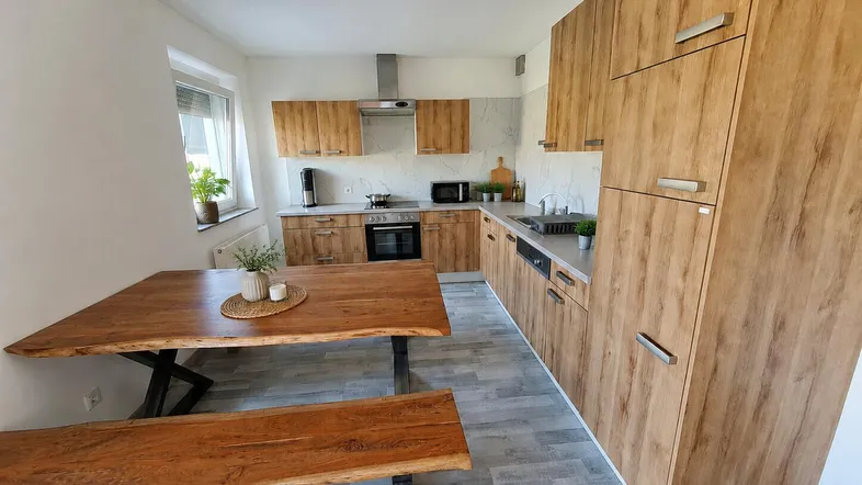Moderne Wohnküche mit Holzfronten, Essbereich und Fenster für natürliches Licht.