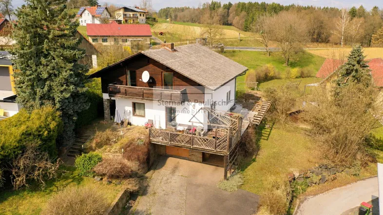 Ländliches Einfamilienhaus mit Balkon und Terrasse in grüner Umgebung.