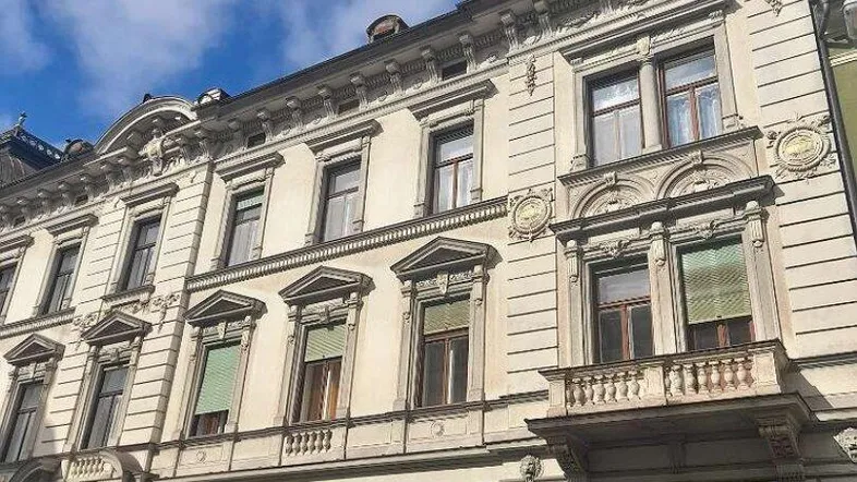Historische Fassade eines Altbaus mit dekorativen Elementen und einem kleinen Balkon.