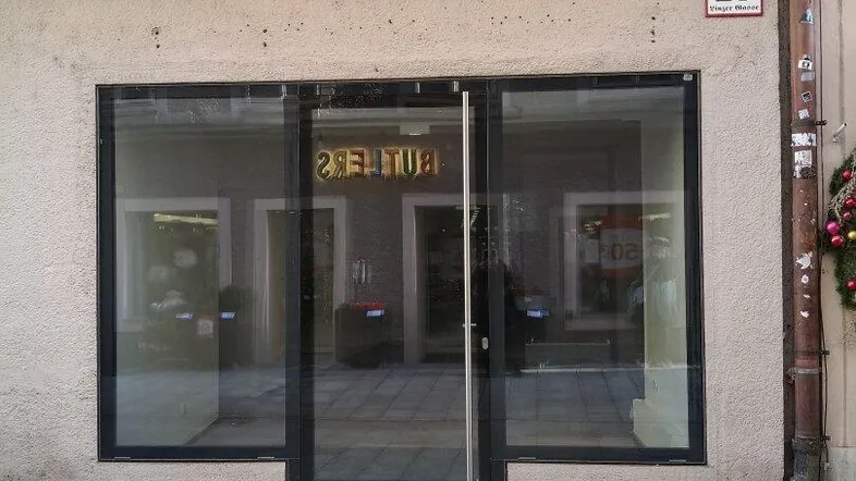 Die Fassade des Gebäudes mit großen Schaufenstern und einem Eingangsbereich zur Straße hin.