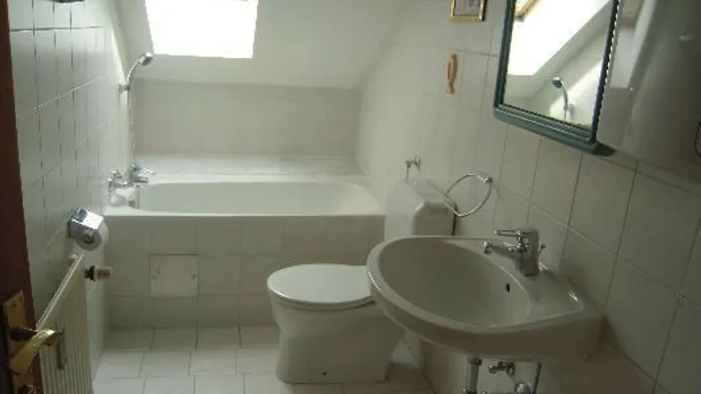Helles Badezimmer im Dachgeschoss mit Badewanne, WC, Waschbecken und Dachfenster.