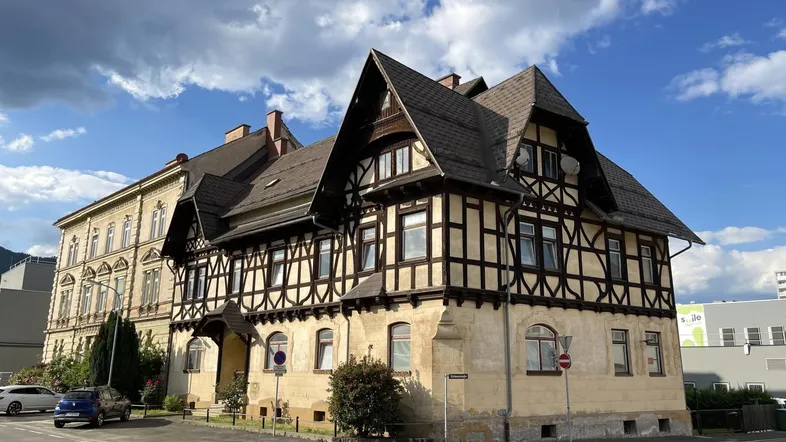 Historisches Gebäude mit markanter Fachwerkfassade und Satteldach unter blauem Himmel.