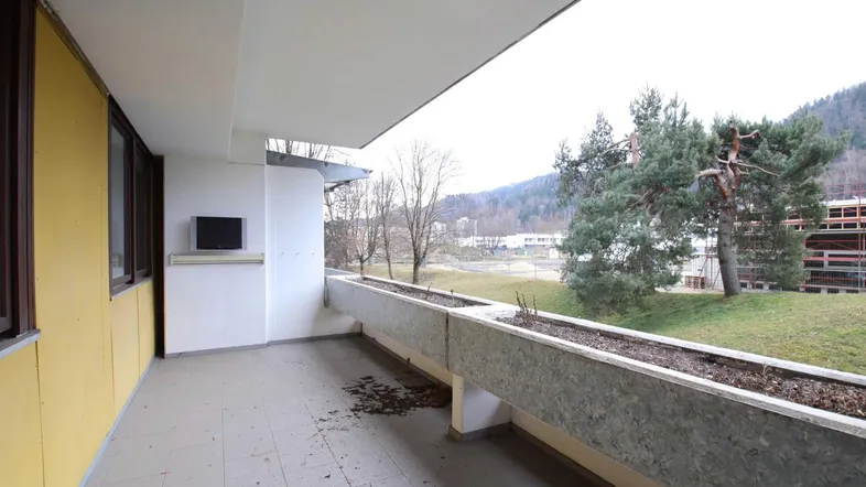 Geräumiger Balkon mit Fliesenboden, Blumenkästen und Blick ins Grüne.