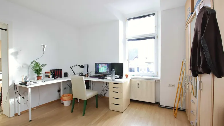 Helles Arbeitszimmer mit Schreibtisch, Computern und Holzfußboden, ideal für Home-Office.