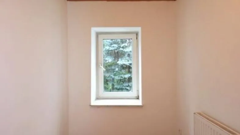 Kleiner, heller Raum mit Holzdecke, Parkettboden und einem Fenster zur Natur.