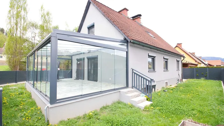 Modernes Einfamilienhaus mit großem, lichtdurchflutetem Wintergarten und angrenzendem Gartenbereich.