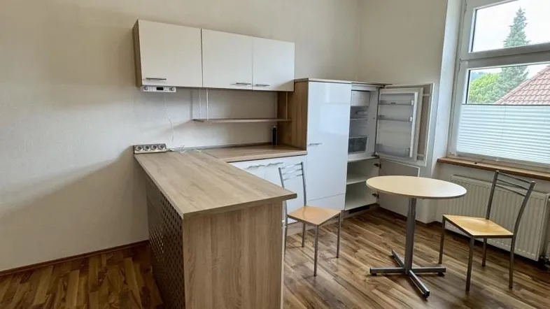 Moderne Küche mit Laminatboden, weißen und holzfarbenen Schränken sowie einem kleinen Essbereich.