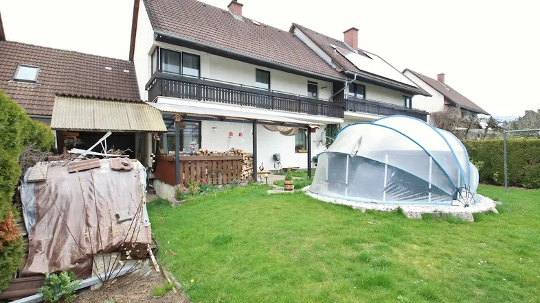 Hinterhof mit grünem Rasen, kleinem Pool und überdachtem Sitzbereich am Haus.