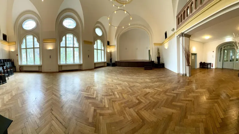 Großer Saal mit Fischgrätparkett, hohen Gewölbedecken und großen Bogenfenstern, ideal für Veranstaltungen.