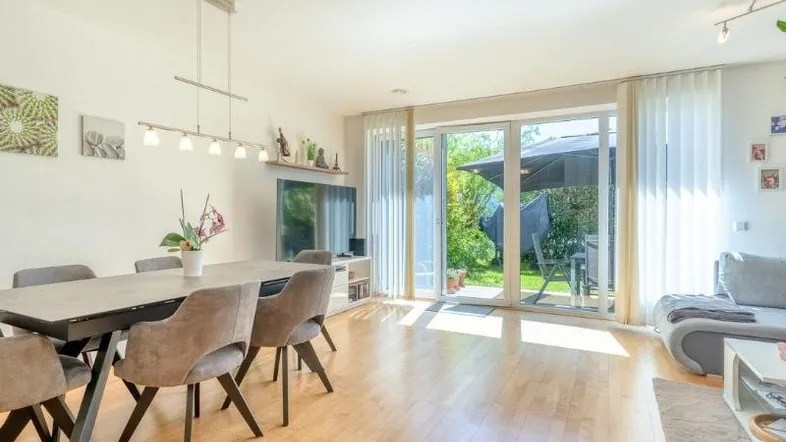 Helles Wohn- und Esszimmer mit Holzboden und Zugang zur Terrasse mit Gartenblick.