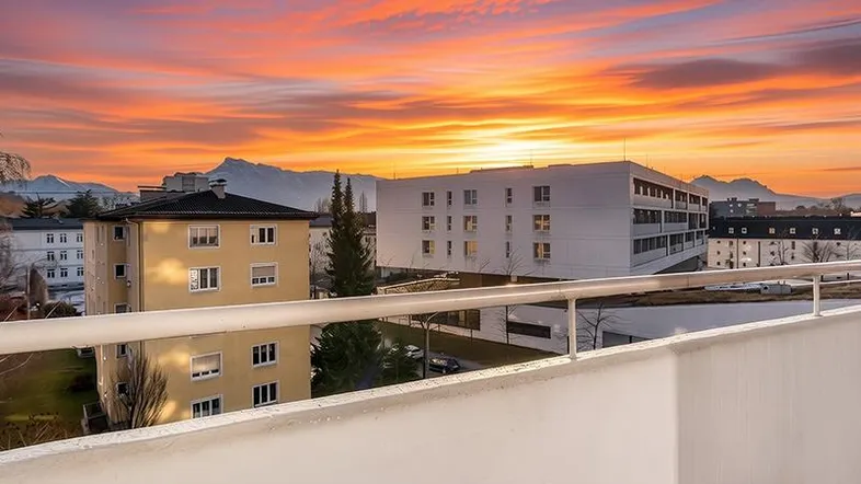 Spektakulärer Sonnenuntergang über der Stadt mit Bergblick von einem Balkon aus.