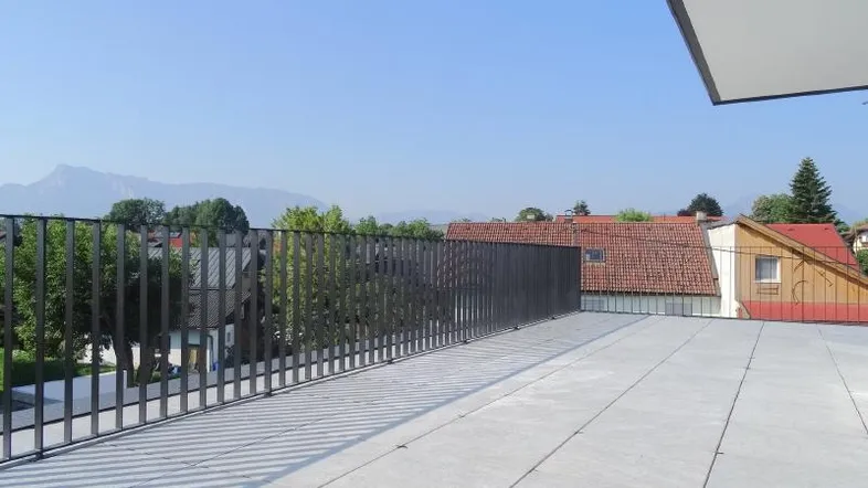 Große Dachterrasse mit moderner Metallbrüstung und weitem Blick auf die Umgebung und Berge.