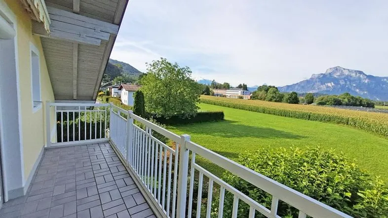 Geräumiger Balkon mit Fliesenboden und weitem Blick über grüne Felder und Berge.