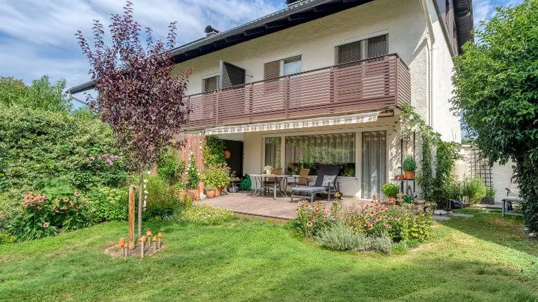 Charmantes Haus mit gepflegtem Garten, Terrasse und Balkon, umgeben von viel Grün.