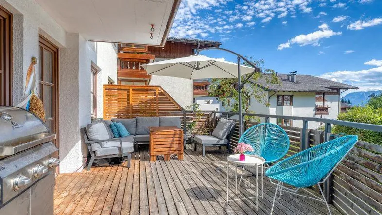 Geräumige Holzterrasse mit modernen Outdoor-Möbeln, Grillbereich und weitem Blick auf die umliegende Landschaft.