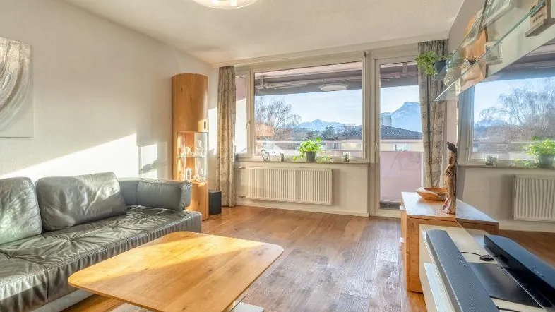 Helles Wohnzimmer mit Holzboden, bequemer Couch und weitem Blick auf die Berge.