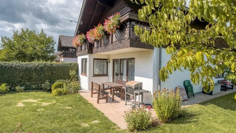 Gemütliche Terrasse mit Gartenmöbeln und Grillbereich, umgeben von einem gepflegten Rasen und Hecken.