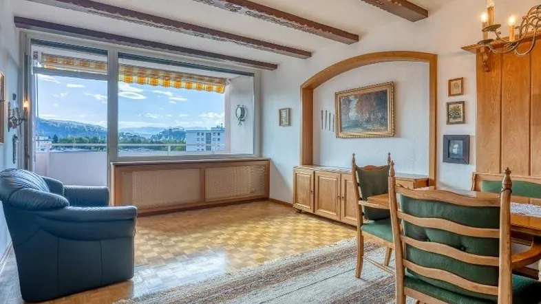 Geräumiger Wohn-Essbereich mit Holzbalkendecke, Parkettboden und Zugang zum Balkon mit Weitblick.