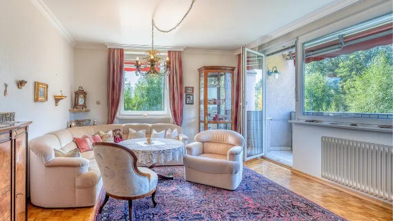 Gemütliches Wohnzimmer mit traditionellem Teppich, Stuckdecke und Zugang zum Balkon.