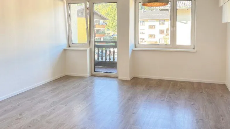 Helles Zimmer mit Laminatboden und direktem Zugang zu einem kleinen Balkon, bietet Blick auf die Umgebung.