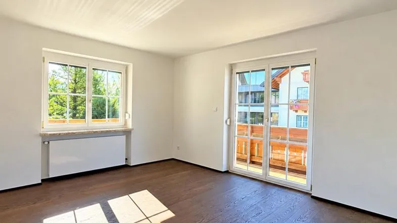 Helles Zimmer mit dunklem Parkettboden und direktem Zugang zu einem Balkon, ideal für Wohnzwecke.