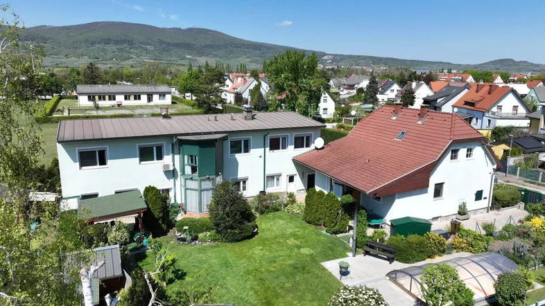 Luftaufnahme eines Wohnhauses mit großem Garten und umliegender Siedlung in ländlicher Umgebung.