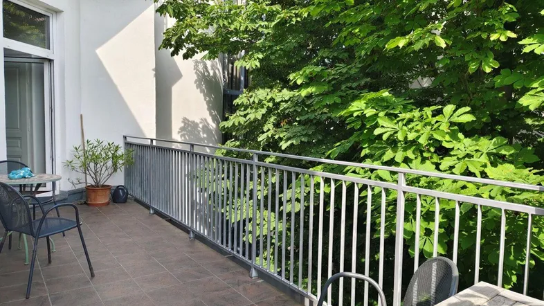 Geräumiger Balkon mit Fliesenboden, Metallgeländer und Blick ins Grüne.
