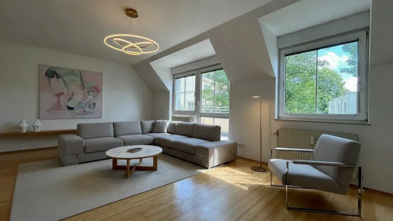 Helles Wohnzimmer mit modernem Ecksofa, Holzboden und großen Dachschrägenfenstern.