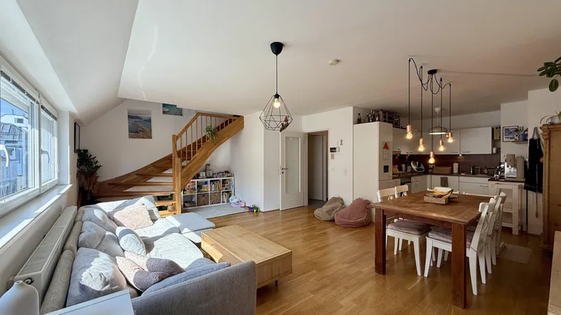 Helles, offenes Wohn- und Esszimmer mit Holzboden, moderner Einrichtung und integrierter Küche.