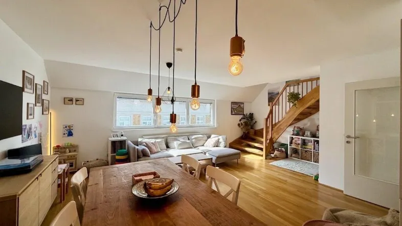 Geräumiger Wohn- und Essbereich mit Holzboden, offener Treppe und viel Tageslicht.