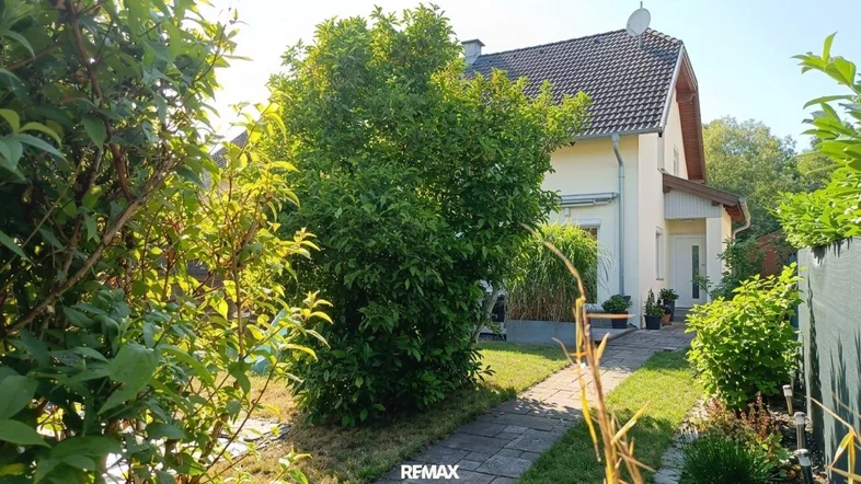 Ein charmantes Haus, umgeben von einem gepflegten Garten mit üppigem Grün und einem Steinweg.