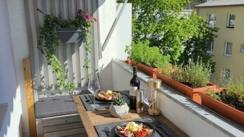 Gemütlicher Balkon mit Holzboden, Esstisch und Blick ins Grüne, ideal für Mahlzeiten im Freien.