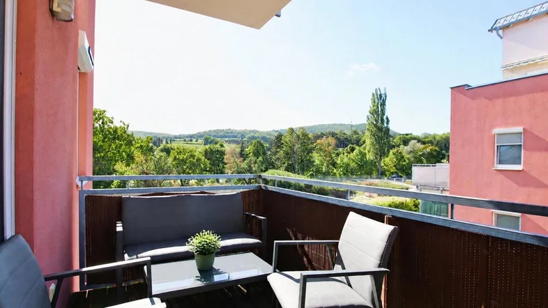 Heller Balkon mit Sitzgelegenheiten und weitem Blick ins Grüne und auf die Landschaft.
