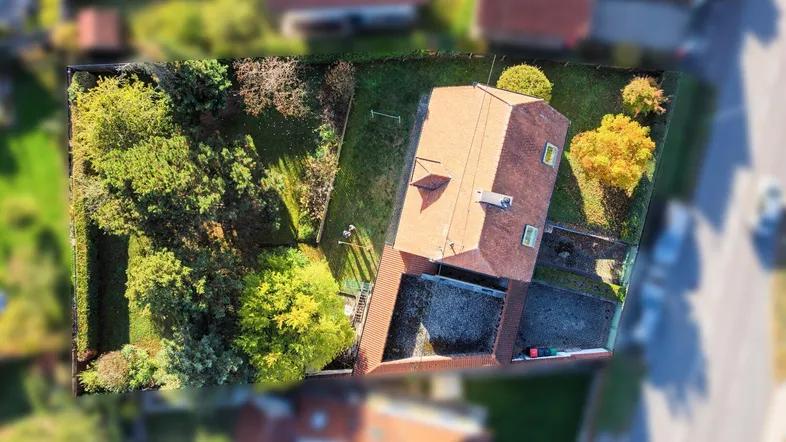 Luftaufnahme eines Einfamilienhauses mit großem Garten und umliegender Wohnbebauung.