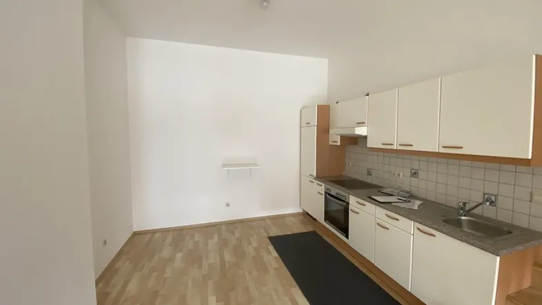Helle Küche mit Einbauküche und Laminatboden in einem offenen Wohnbereich.