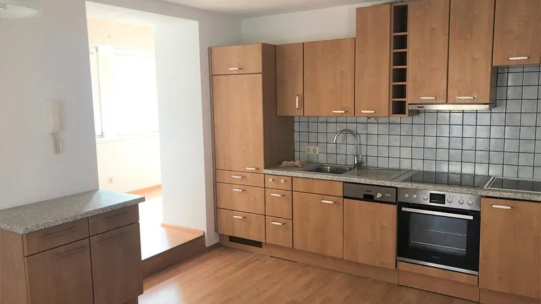 Funktionale Küche mit hellen Holzschränken, Fliesenrückwand und integrierten Geräten.