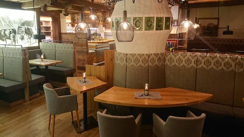 Rustikaler Restaurantbereich mit Holzbalken, gemütlichen Sitzecken und stimmungsvoller Beleuchtung.