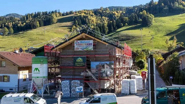 Neubau im Bau mit Gerüst und Blick auf die umliegende Berglandschaft.