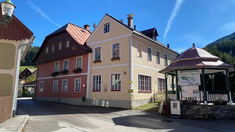 Traditionelle Gebäude an einer Straße mit einem kleinen Pavillon und Bergkulisse.