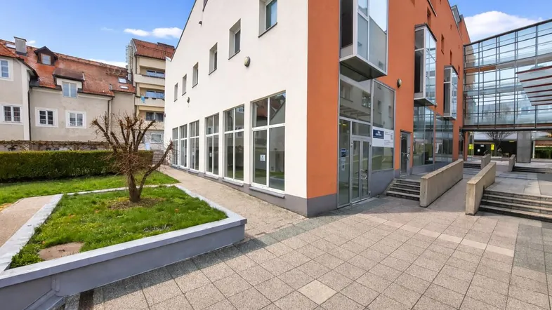 Modernes Gebäude mit großen Fenstern und einer Mischung aus weißen und orangefarbenen Fassaden.