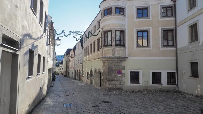 Historische Gasse mit Kopfsteinpflaster und traditionellen Gebäuden unter blauem Himmel.