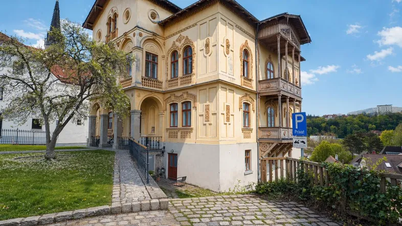 Historisches Gebäude mit kunstvoller Fassade, kleinem Vorgarten und barrierefreiem Zugang.