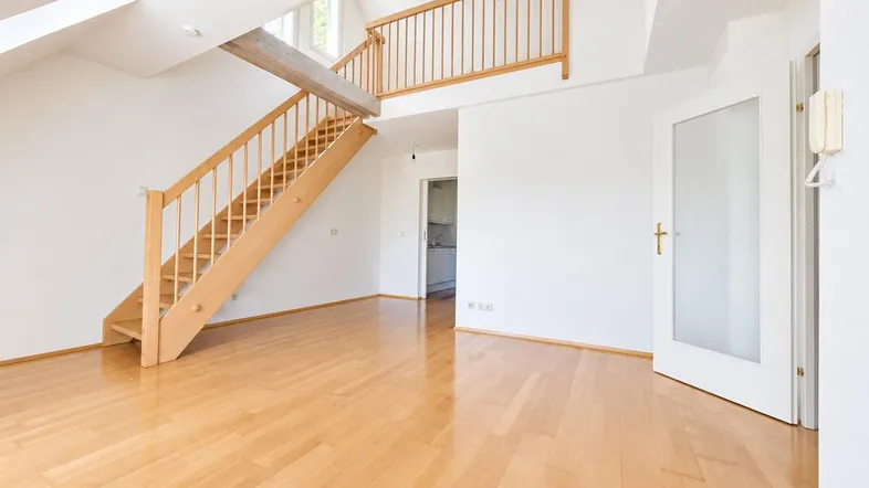 Helles Wohnzimmer mit Holztreppe, Parkettboden und Dachschrägen, das zu einer Galerie führt.