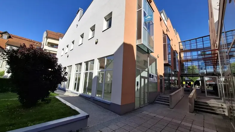 Modernes Geschäftsgebäude mit großen Fensterfronten und gepflegter Grünfläche im Außenbereich.