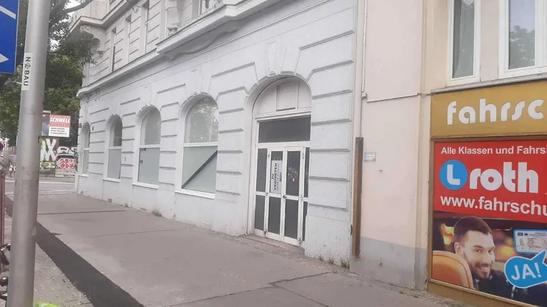 Die Fassade eines älteren Gebäudes an einer Straße mit einem Schild an der Eingangstür.