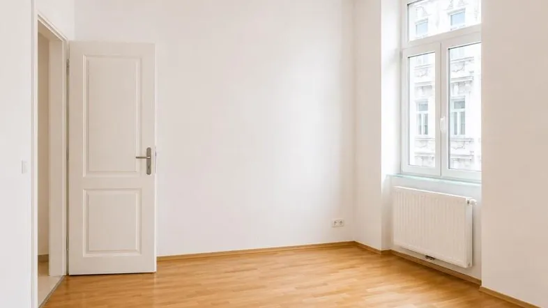 Helles Zimmer mit Parkettboden und großem Fenster, bereit zur individuellen Gestaltung.